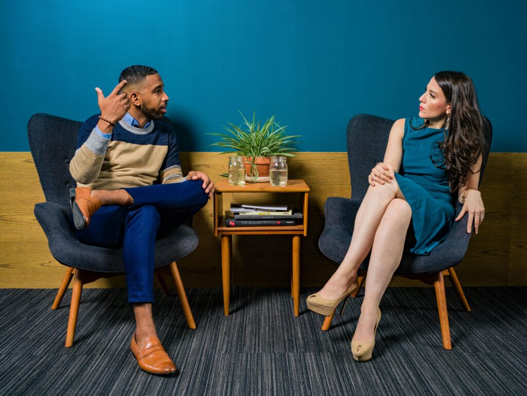 Two professionals on comfortable chairs engaged in conversation